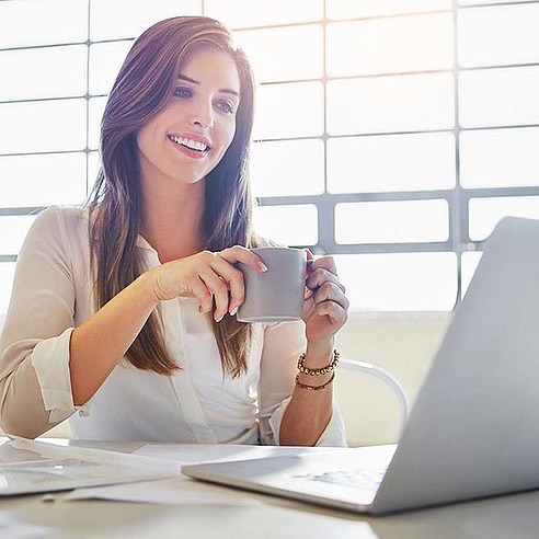 Weibliche Person sitzt am Schreibtisch und trinkt Tee | Tiger Balm
