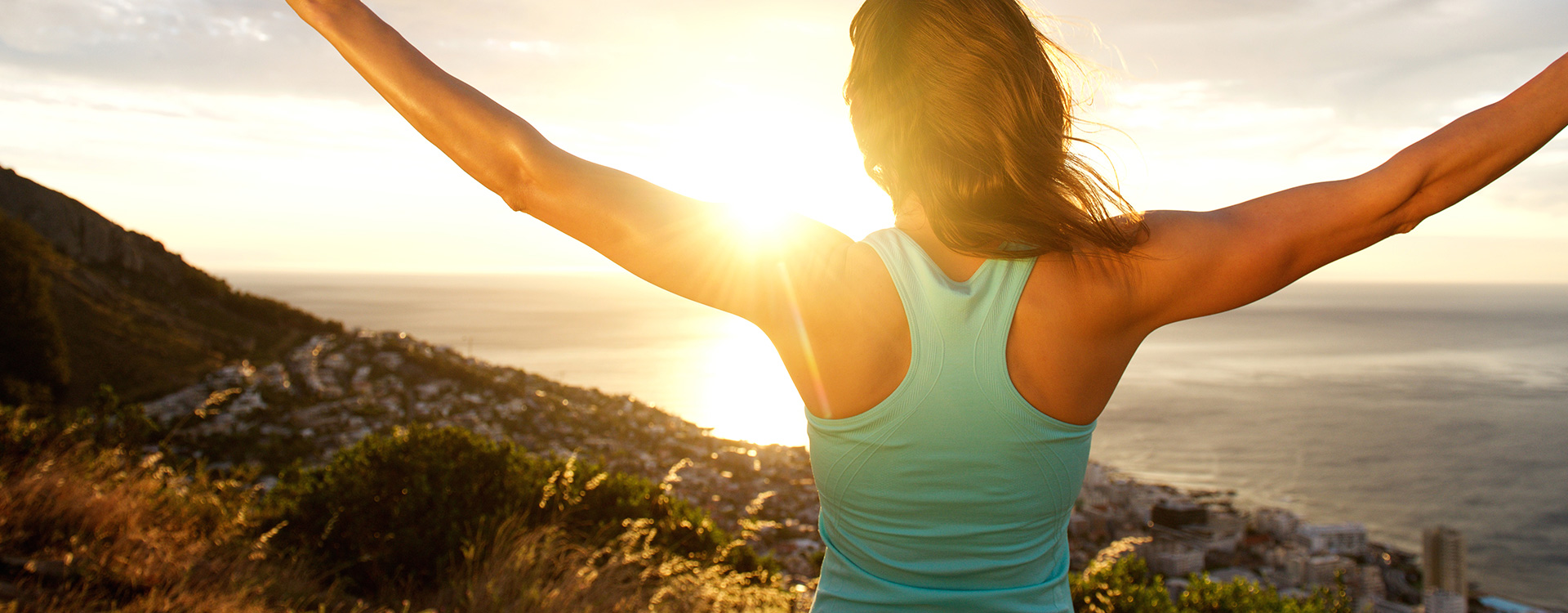 Weibliche Person steckt ihre Arme in dem Sonnenaufgang entgegen | Tiger Balm